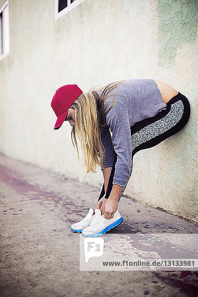 Sportlerin bindet Schnürsenkel  während sie auf dem Bürgersteig steht