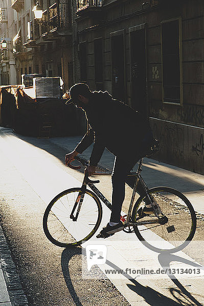 Mann fährt bei Sonnenuntergang Fahrrad auf einem Fußweg