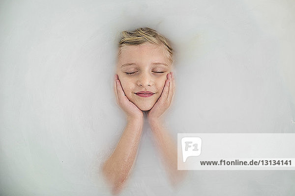 Overhead view of girl with closed eyes resting in bathtub