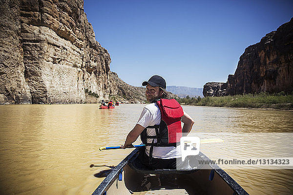 Porträt eines lächelnden Mannes mit Ruder  der in einem Boot auf dem Fluss im Big-Bend-Nationalpark sitzt