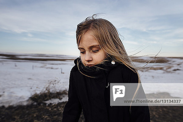 Girl standing on field against sky during winter