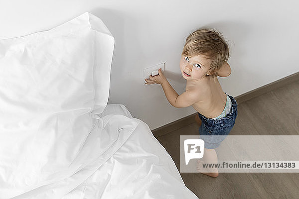 High angle portrait of shirtless baby girl standing by bed on floor at home