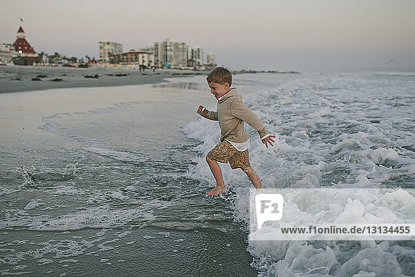 Side view of playful boy running on shore