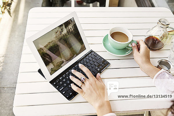 Ausschnitt eines Bildes einer Frau  die einen Tablet-Computer im Straßencafé benutzt