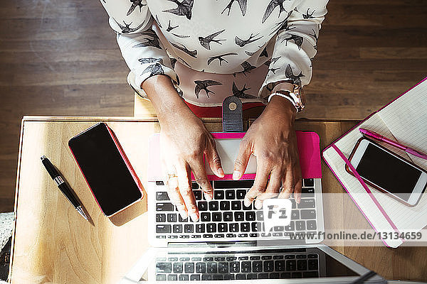 Mittelsektion einer Geschäftsfrau mit Laptop-Computer am Tisch im Büro