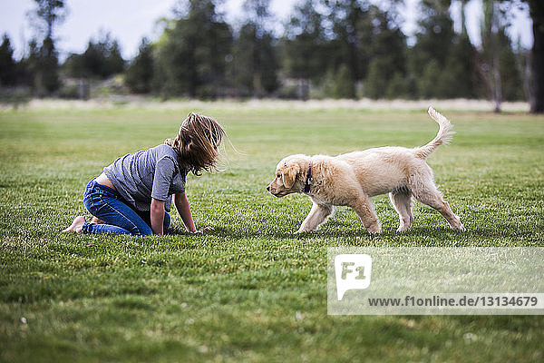 Side view of girl playing with dog on field