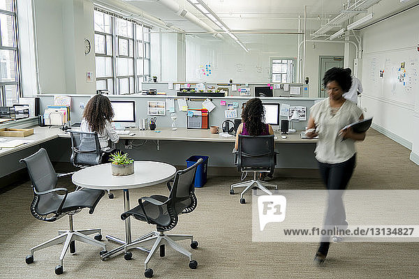 Geschäftsfrauen nutzen Desktop-Computer  während sie im Büro am Schreibtisch sitzen