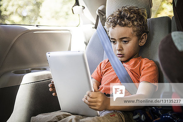 Boy using tablet computer while sitting in car