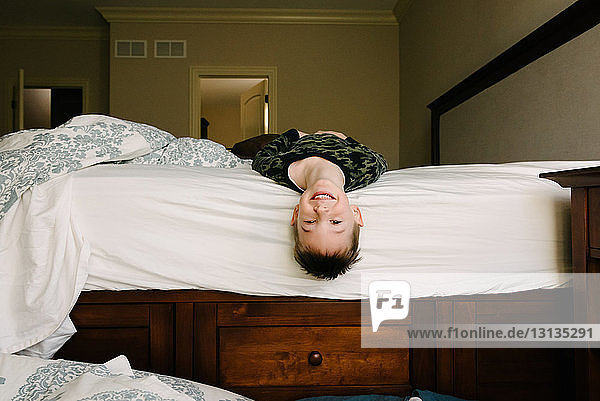 Porträt eines glücklichen Jungen  der zu Hause auf dem Bett liegt