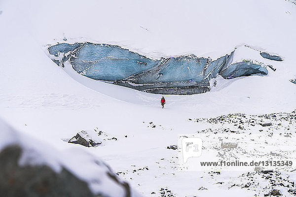 Mitteldistanzansicht eines Wanderers  der auf schneebedeckter Landschaft läuft