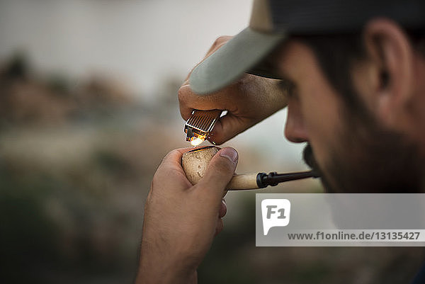 Cropped image of man lighting smoking pipe