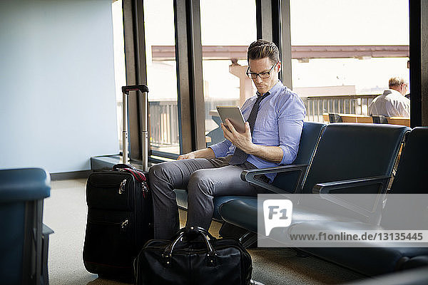 Businessman using tablet computer while sitting in waiting area at subway station