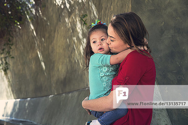 Mutter küsst Tochter  während sie im Park steht