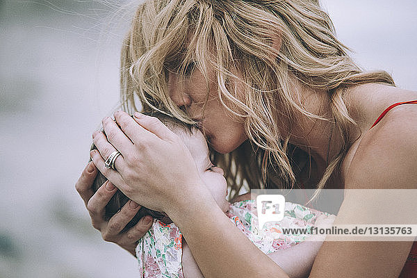 Frau mit blonden Haaren küsst Tochter