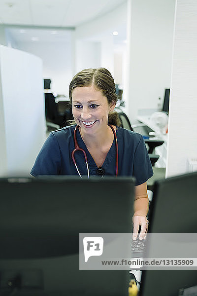 Fröhliche Ärztin benutzt Desktop-Computer im Krankenhaus