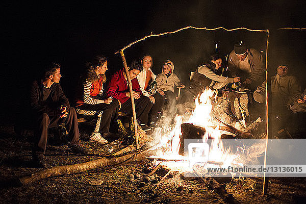 Friends sitting near campfire at night