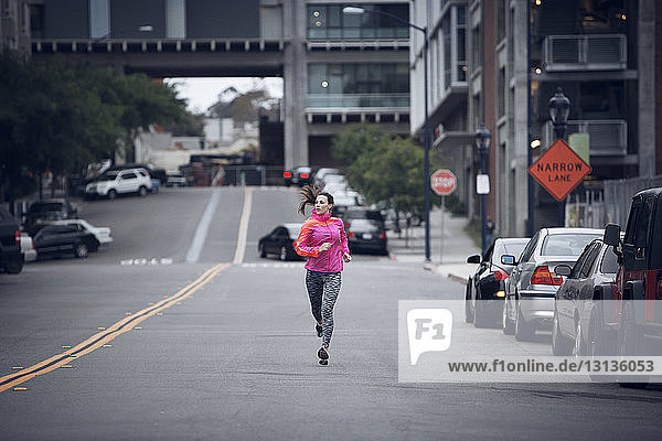 Entschlossene Sportlerin läuft in voller Länge auf der Straße in der Stadt