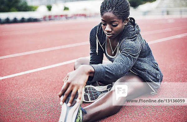 Entschlossene Athletin berührt die Zehen an den Laufstiften