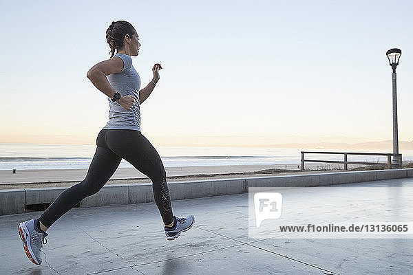 Side view of woman jogging against clear sky