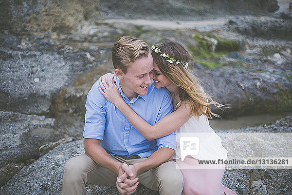 Glückliches Paar sitzt auf einem Felsen am Strand