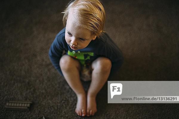 High angle view of boy sitting on floor at home