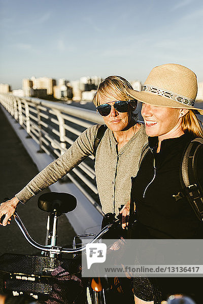 Mother and daughter with bicycles on pier in city