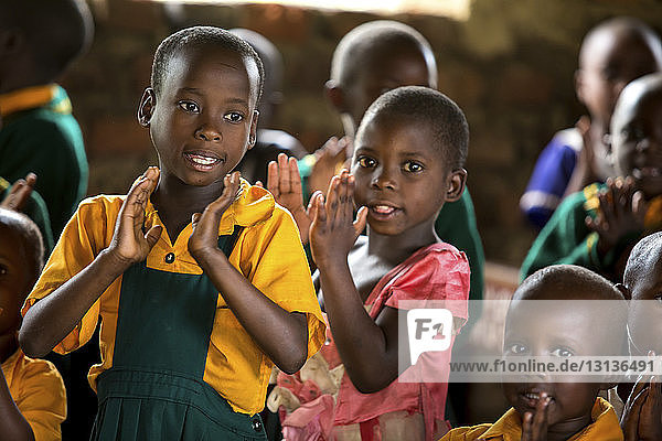Kinder klatschen im Stehen im Klassenzimmer in die Hände