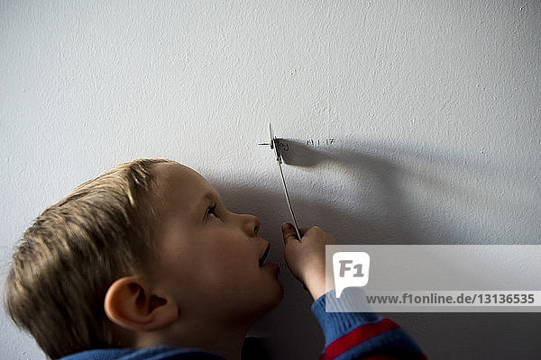 Nahaufnahme eines Jungen  der zu Hause an der Wand mit einem Spielzeug spielt