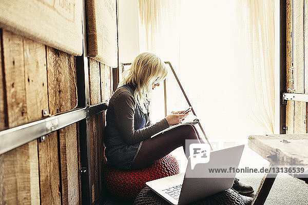 Geschäftsfrau benutzt Smartphone bei der Arbeit im Kreativbüro