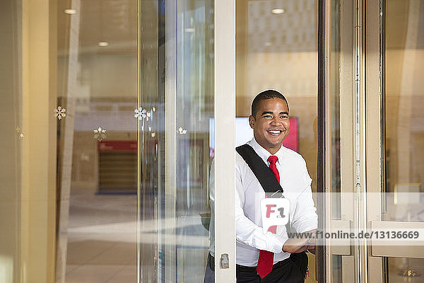 Smiling businessman standing at glass doorway