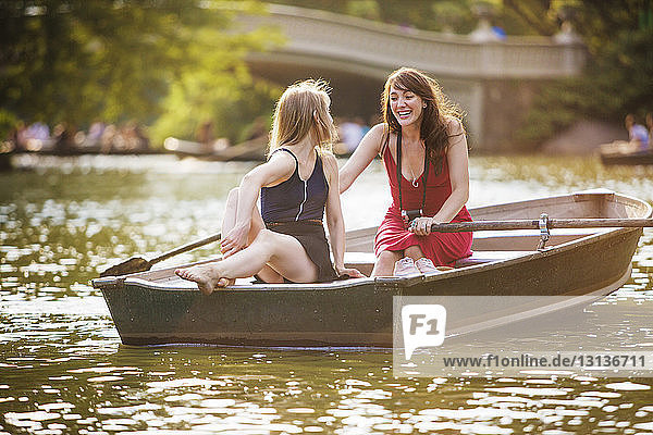 Glückliches lesbisches Paar beim Bootfahren auf dem See im Park