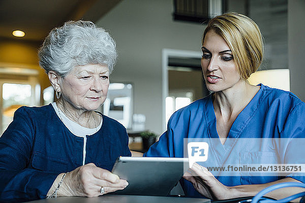 Heimpflegekraft unterstützt ältere Frau bei der Verwendung eines Tablet-Computers