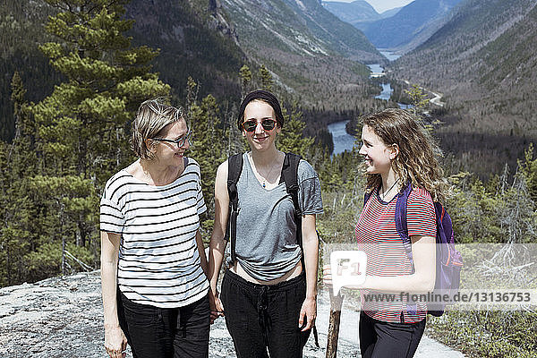 Smiling mother with daughters hiking against mountains