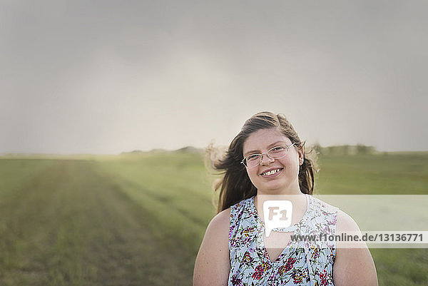 Porträt eines übergewichtigen Teenagers  der auf einem Feld gegen den Himmel steht