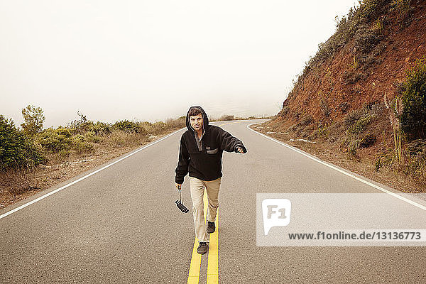Portrait of man holding binocular while walking on mountain road