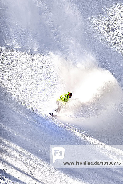 Mann beim Snowboarden auf schneebedecktem Berg