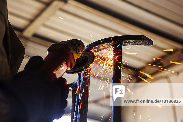 Beschnittenes Bild eines Handwerkers  der in der Fabrik Metall poliert