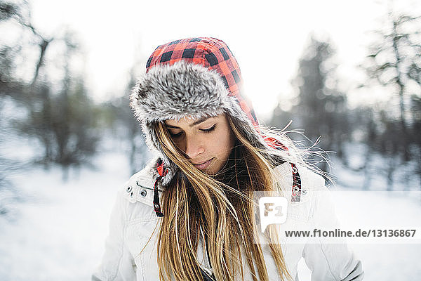 Close-up of woman wearing fur hat at snow covered field