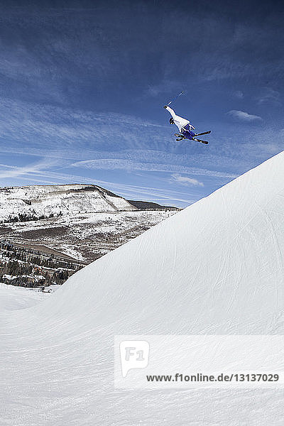 Niedrigwinkelansicht eines Skifahrers beim Skifahren auf einem schneebedeckten Berg gegen den Himmel