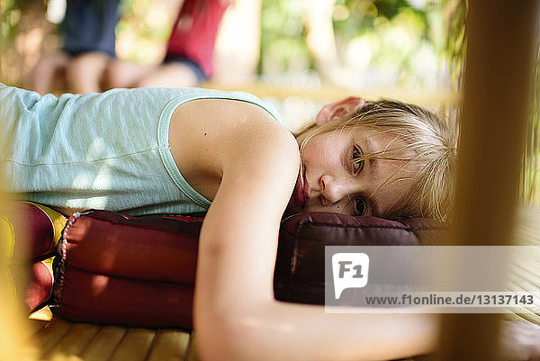 Portrait of girl lying on pillow at porch