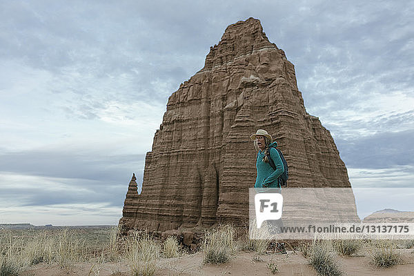 Wanderin steht vor Felsformationen und bewölktem Himmel in der Wüste