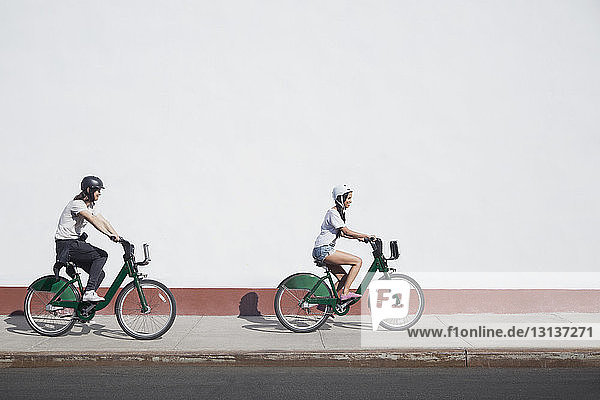 Fahrradfahren zu zweit auf dem Bürgersteig bei Sonnenschein