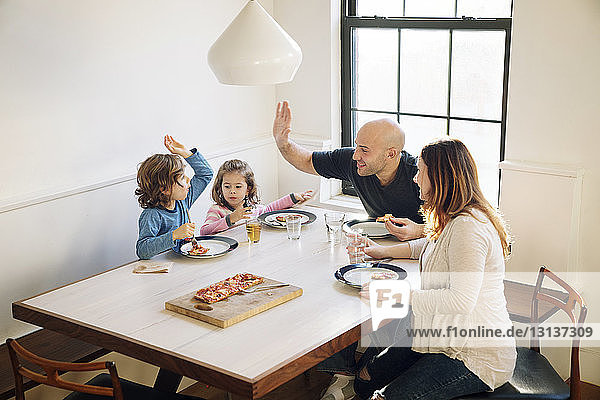 Family enjoying while eating pizza at dining table in home