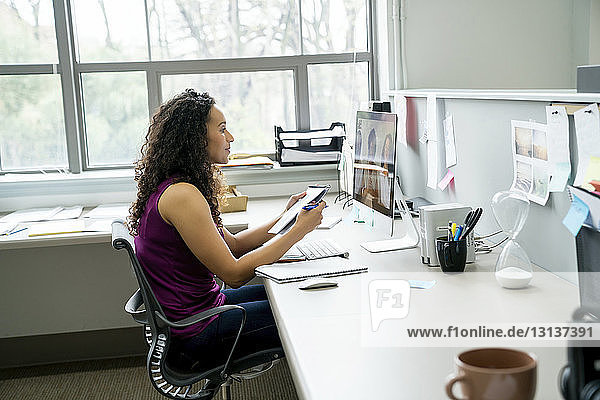 Seitenansicht einer Geschäftsfrau  die mit Kollegen diskutiert Videokonferenz mit einem Kollegen über einen Desktop-Computer im Büro
