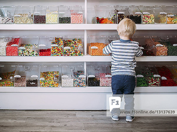 Rear view of boy standing against shelves in store