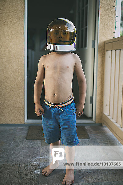 Porträt eines Jungen mit Weltraumhelm auf der Veranda stehend