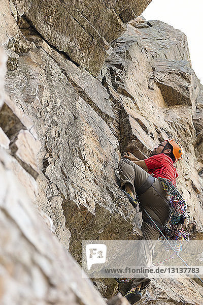 Niedrigwinkelansicht eines Wanderers  der an einer Felsformation klettert