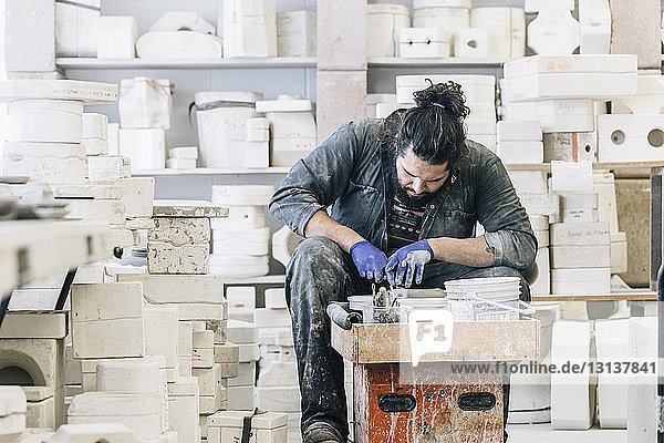 Craftsman using pottery wheel while working in art studio