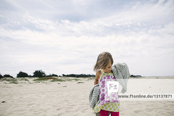 Girl standing on sand at beach against sky