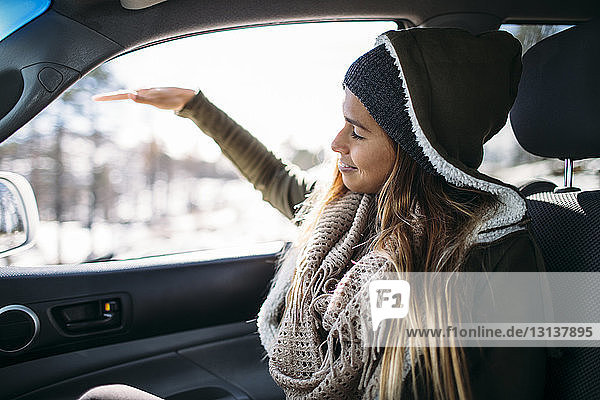 Glückliche junge Frau genießt im Winter im Auto